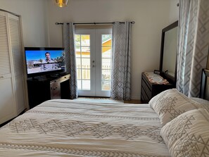 A hotel room with a bed, a television, a dresser, and a balcony door. - Alameda Luxury 2BR 2BA house, AC, near Alameda ferry to San Francisco, parking. (Alameda)