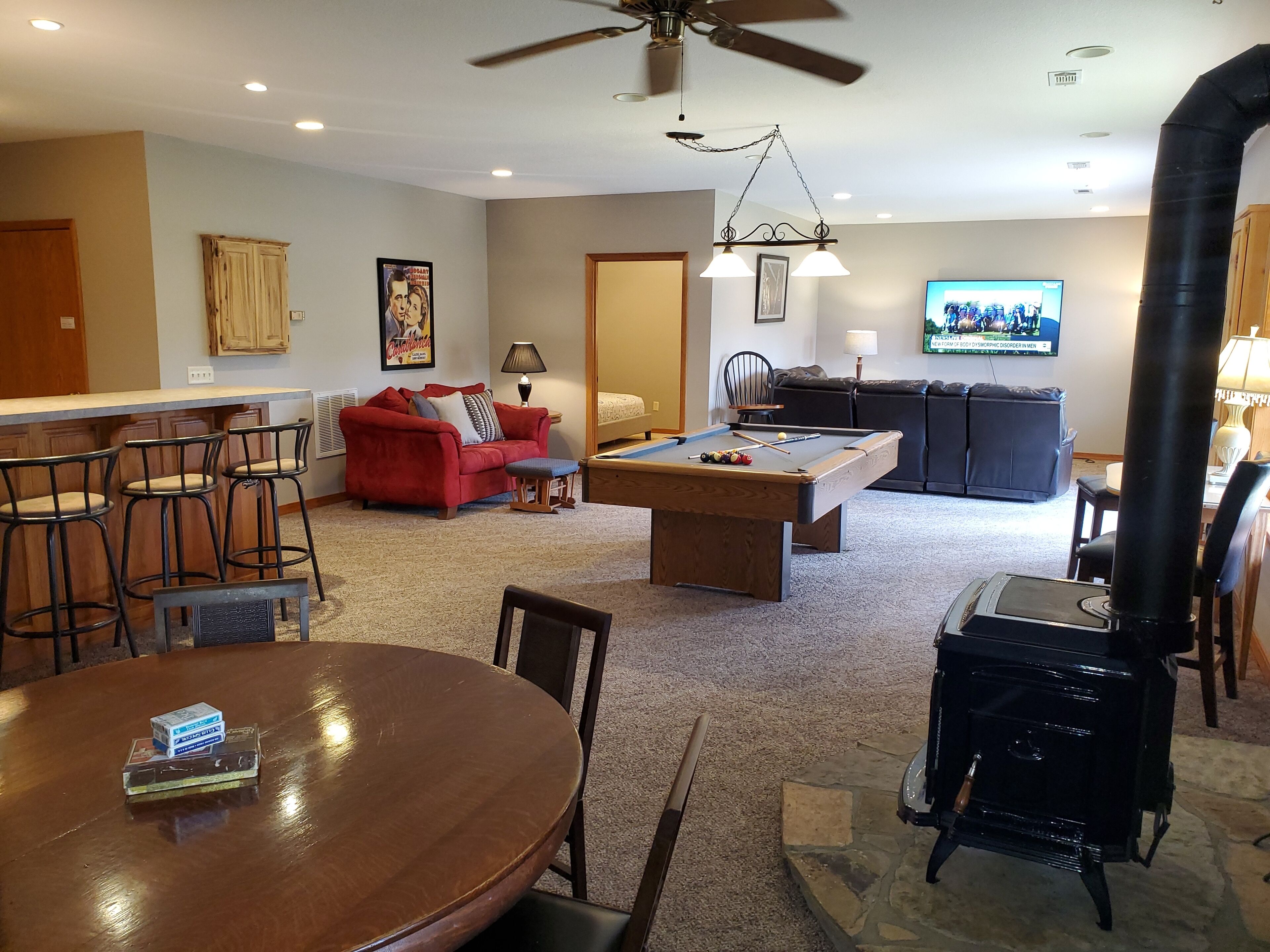A living room with a pool table, red sofa, and a ceiling fan.