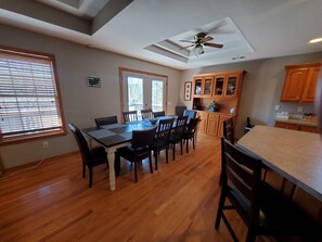 A dining area with a wooden table and chairs, a ceiling fan, and wooden cabinets in the background.