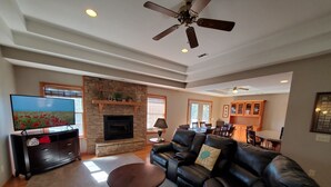 A living room with a stone fireplace, leather sofa, and a television.