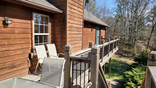 A wooden deck with outdoor seating and a view of a forested area.