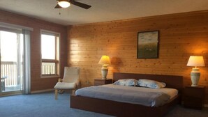 Une chambre avec un mur en bois, un lit avec deux oreillers, une chaise et deux lampes de chevet.