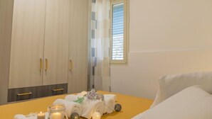 A bedroom with a bed, a bedside table with candles, and a wardrobe.