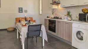 A compact kitchen with a dining area, a washing machine, and a small table with a chair.