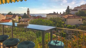 Una terraza con mesa y sillas, con vistas a un pueblo con edificios y una torre.