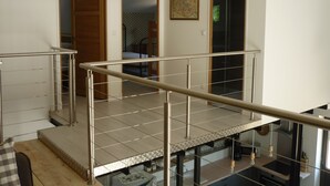 A modern interior with a staircase, a kitchen area, and a bedroom visible through an open door. - Workshop n°2 for 6 with shared pool and sauna for lazy days (Semur-en-Auxois)