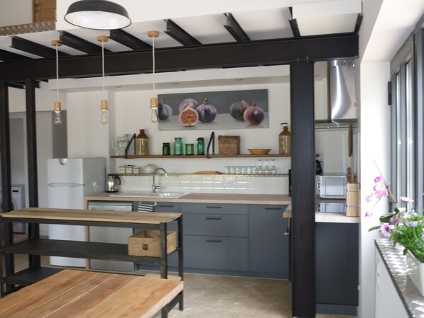 Una cocina moderna con una mesa de madera y un banco, un fregadero y objetos decorativos en estantes.