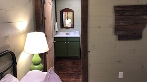 A narrow hallway with a bed on the left, a green cabinet with a sink in the center, and a mirror on the wall. - 3br2bath farmhouse 7min d'town Mem ❤️1 pet free 2nd pet considered for fee  (Mound City)