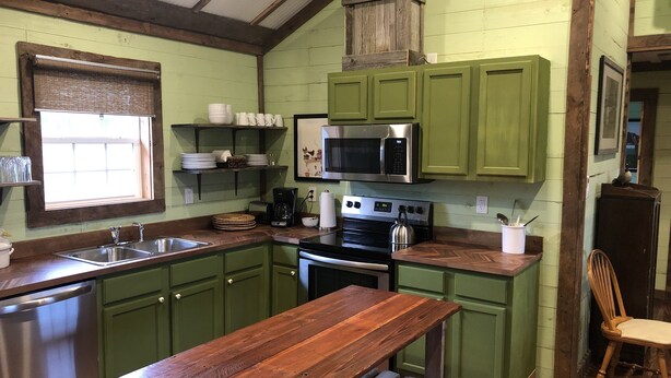 A kitchen with green cabinets, a wooden table, a stainless steel sink, a microwave, and a stove. - 3br2bath farmhouse 7min d'town Mem ❤️1 pet free 2nd pet considered for fee  (Mound City)