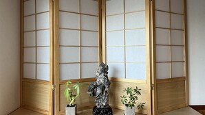 A room with a traditional Japanese shoji screen, a stone sculpture, and two potted plants. - Karin Doo Hotel (Tomisato)