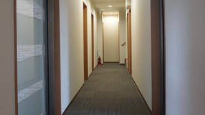 A hotel hallway with carpeted floors, wooden doors, and a fire extinguisher on the wall. - Karin Doo Hotel (Tomisato)