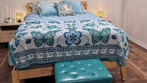 Une chambre à coucher comprenant un lit, une table de chevet, un miroir rond fixé au mur et un élément décoratif mural.