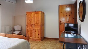 A bedroom with a bed, wooden wardrobe, TV on a stand, and a chair. - Attic overlooking the sea of the Cyclops (Vampolieri)