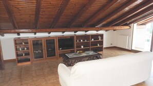 A living room with a white sofa, wooden shelves with decorative items, and a tiled floor. - Attic overlooking the sea of the Cyclops (Vampolieri)
