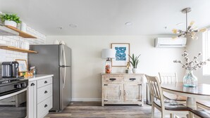 A modern kitchen with a stainless steel refrigerator, wooden cabinets, and a dining area with a table and chairs.
