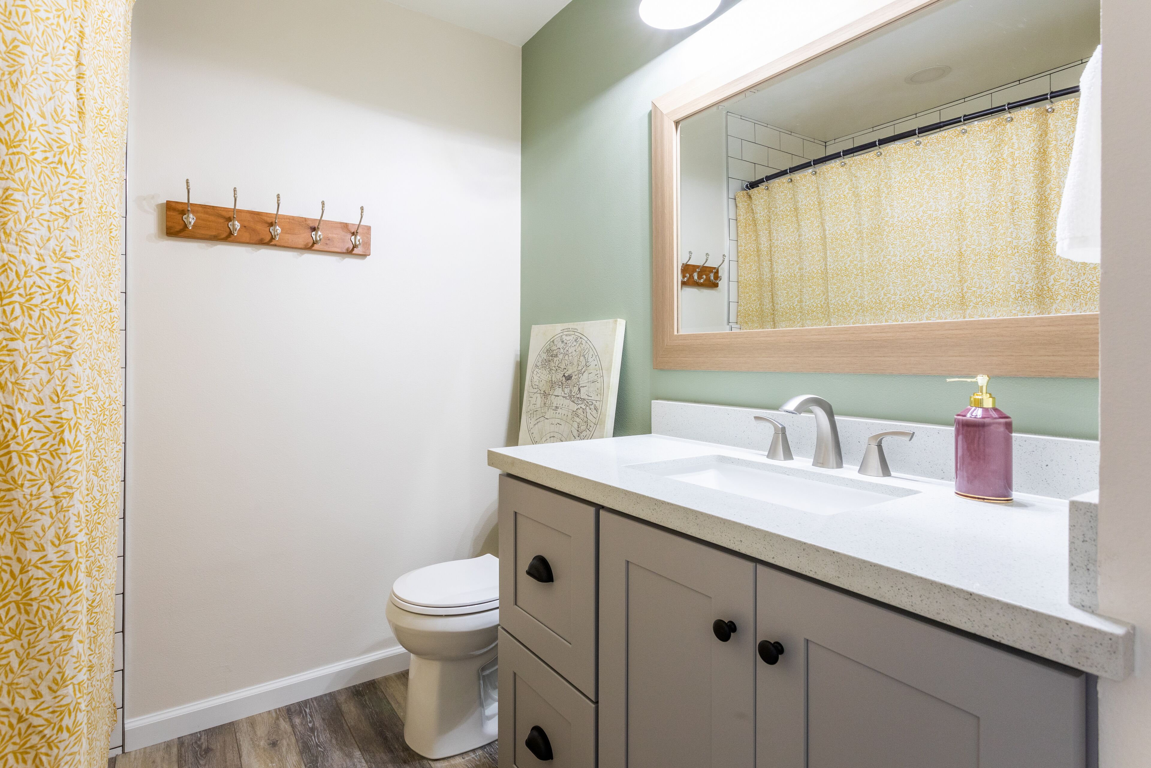 A bathroom with a white sink, a mirror, a toilet, and a wooden coat rack.