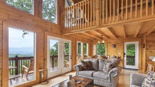 Een ruime houten chalet met een slaapkamer op de entresol, een gezellige woonkamer met een bank en salontafel, en grote ramen met een prachtig uitzicht.