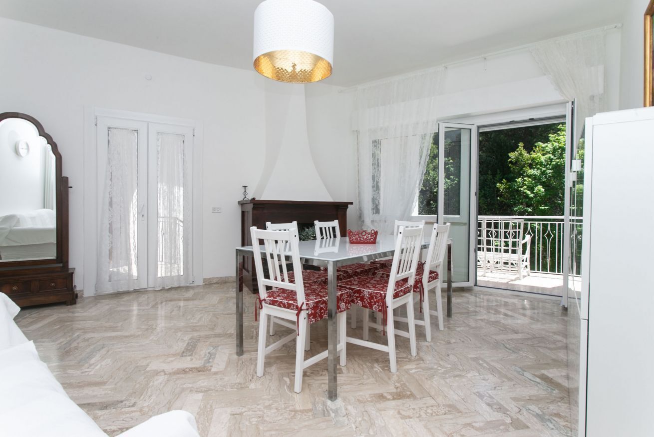 A dining area with a table and chairs, a chandelier, a fireplace, and a view of the outdoors.