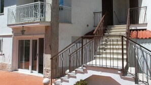 Un edificio de varios pisos con balcones, una escalera y una puerta.