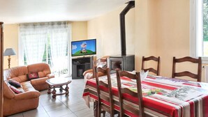 A living room with a sofa, a TV, a fireplace, and a dining table with chairs. - Homerez - House in Saint-Alban (Saint-Alban)