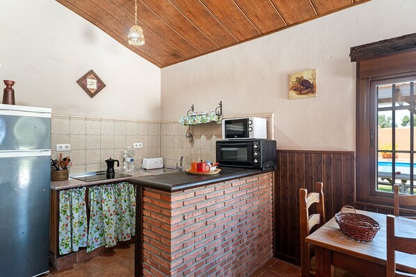 Una cocina con una isla de ladrillo, un microondas y una ventana con vistas.