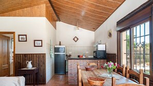 Una cocina con vigas de madera, una mesa de comedor con sillas, un refrigerador y un ventanal con vistas.