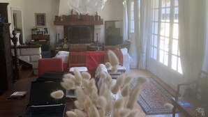 Uma sala de estar com lareira, televisão e uma grande janela com cortinas.