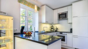 Eine moderne Küche mit weißen Schränken, einer schwarzen Arbeitsplatte und einem eingebauten Backofen.