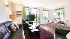 Ein Wohnzimmer mit einer schwarzen Ledersofa, einem Couchtisch und einem Essbereich mit Tisch und Stühlen.