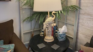 Een ronde, zwarte tafel met een lamp, een zakdoos en een decoratief object.