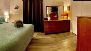 Een slaapkamer met een bed, nachtkastjes, een dressoir, een spiegel en een wandplank.