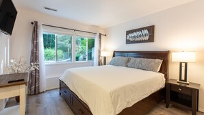 A bedroom with a bed, bedside lamps, a TV, and a window with curtains.