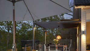 An outdoor deck with a dining area, chairs, and a grill.