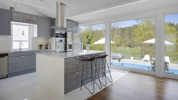 A modern kitchen with a central island, stainless steel appliances, and a view of a backyard with outdoor seating.