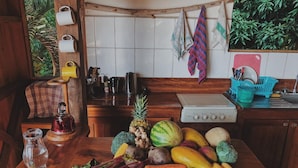 A kitchen counter with fresh fruits and vegetables, a kettle, and a water jug.