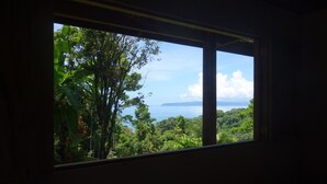 A room with a large window overlooking a lush landscape and a body of water.