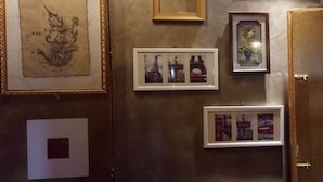 Una pared decorada con diversos cuadros, incluyendo un boceto, fotografías de monumentos parisinos y una planta enmarcada.