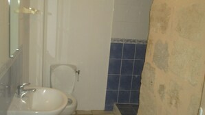 Casa de banho com lavatório branco, sanita e área de chuveiro revestida a azulejos azuis.