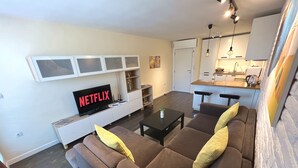 Una sala de estar moderna con un sofá marrón, una mesa de centro y un televisor de pantalla plana mostrando 'NETFLIX'.