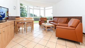 Un salon moderne avec un canapé, des fauteuils, une table basse et un téléviseur.