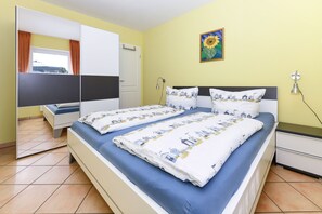 Ein Schlafzimmer mit zwei Betten, einem Kleiderschrank, einem Nachttisch, einer Lampe und einem Bild an der Wand.