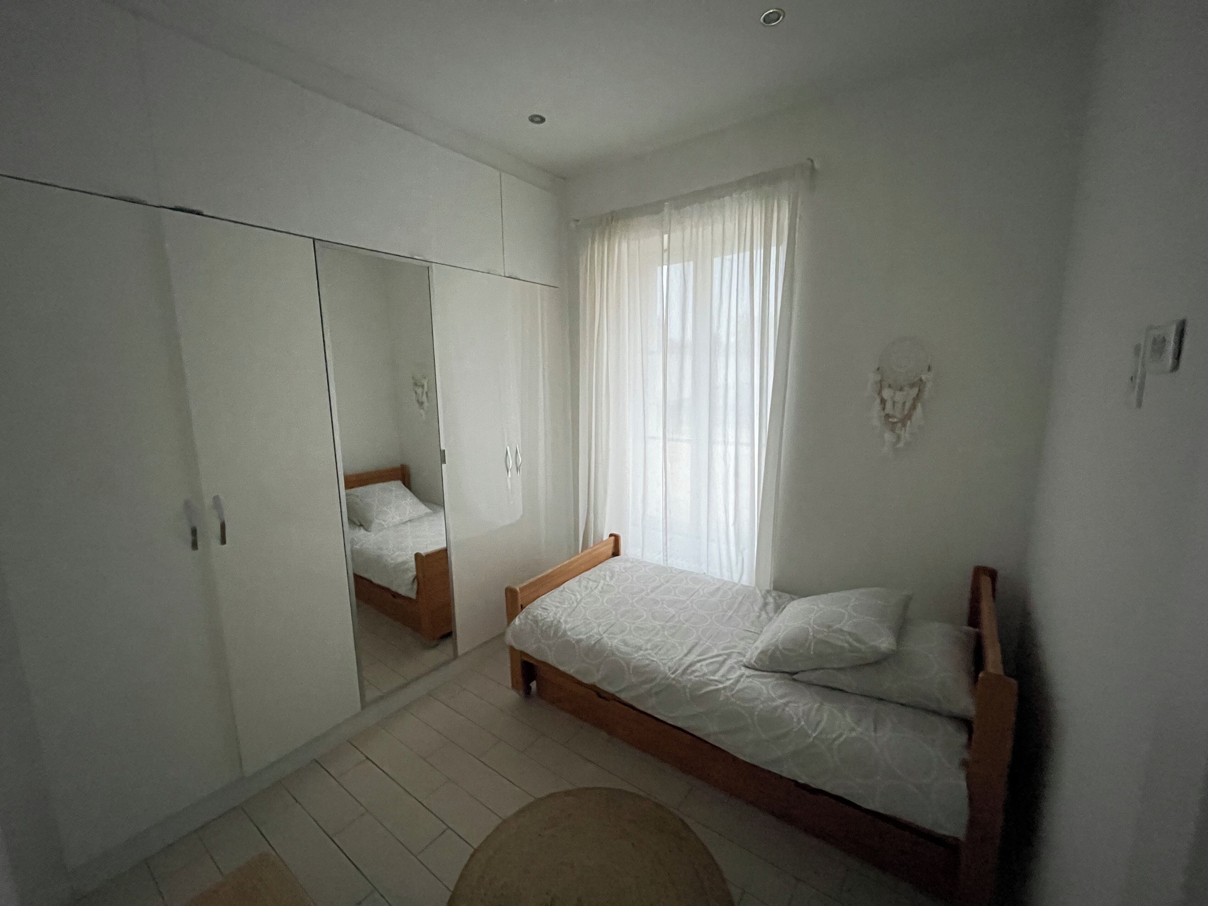 Quarto com cama, guarda-roupa e espelho.