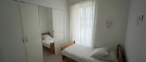 Quarto com cama, guarda-roupa e espelho.