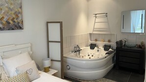 Ein modernes Badezimmer mit einer freistehenden Badewanne, einem Waschtisch mit einer Glasbecken-Spüle und einem großen Spiegel über dem Waschbecken.