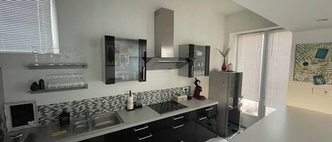 Una cocina moderna con armarios negros, un lavamanos de acero inoxidable y un horno empotrado.