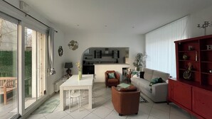 Ein modernes Wohnzimmer mit Essbereich, einer Couch, einem roten Schrank und einer Küche im Hintergrund.