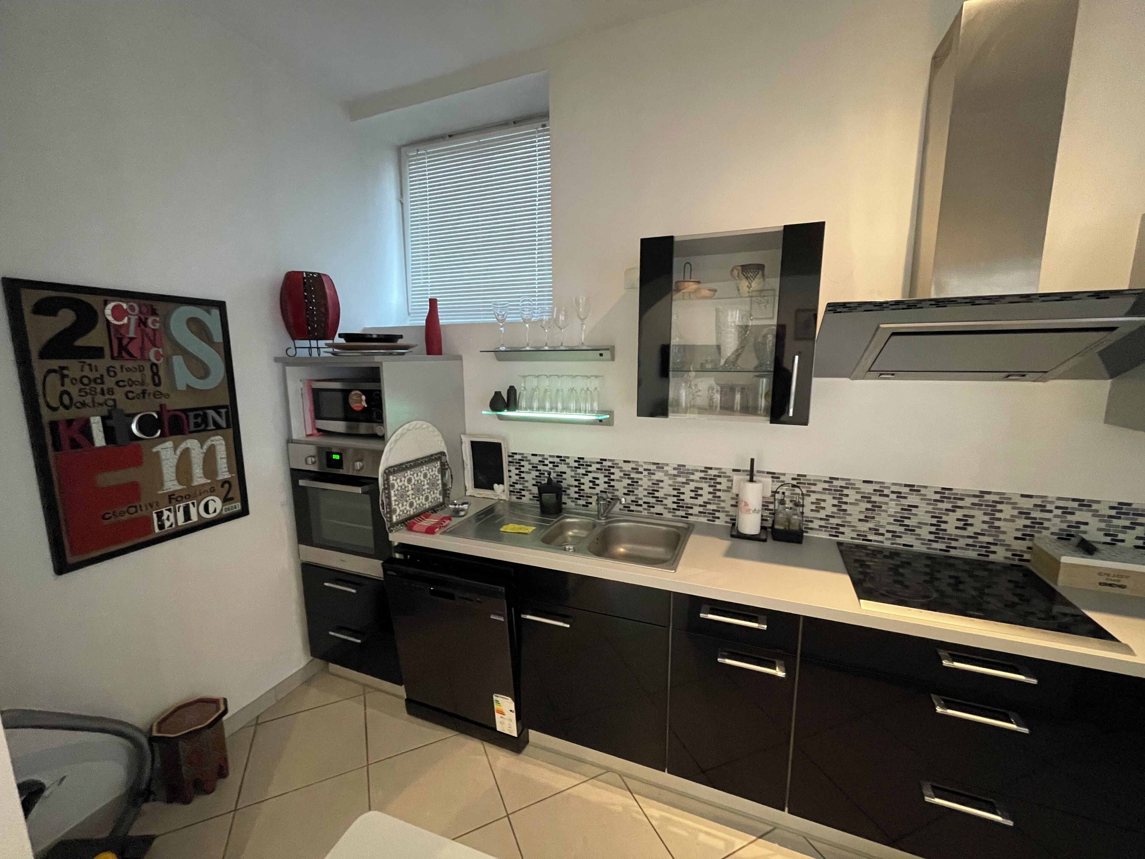 A modern kitchen with black cabinets, a stainless steel sink, and a microwave.