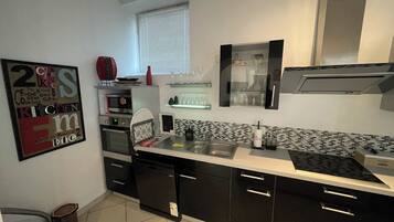 A modern kitchen with black cabinets, a stainless steel sink, and a microwave.