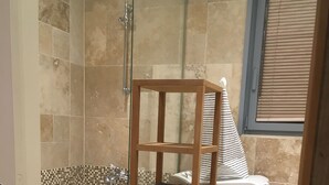 Un baño con bañera, una silla de madera, un perchero para toallas y una ventana con persianas.