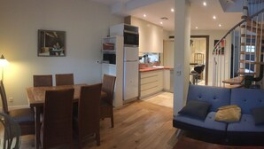 Una sala de estar moderna con comedor, cocina y una escalera que sube a un nivel superior.